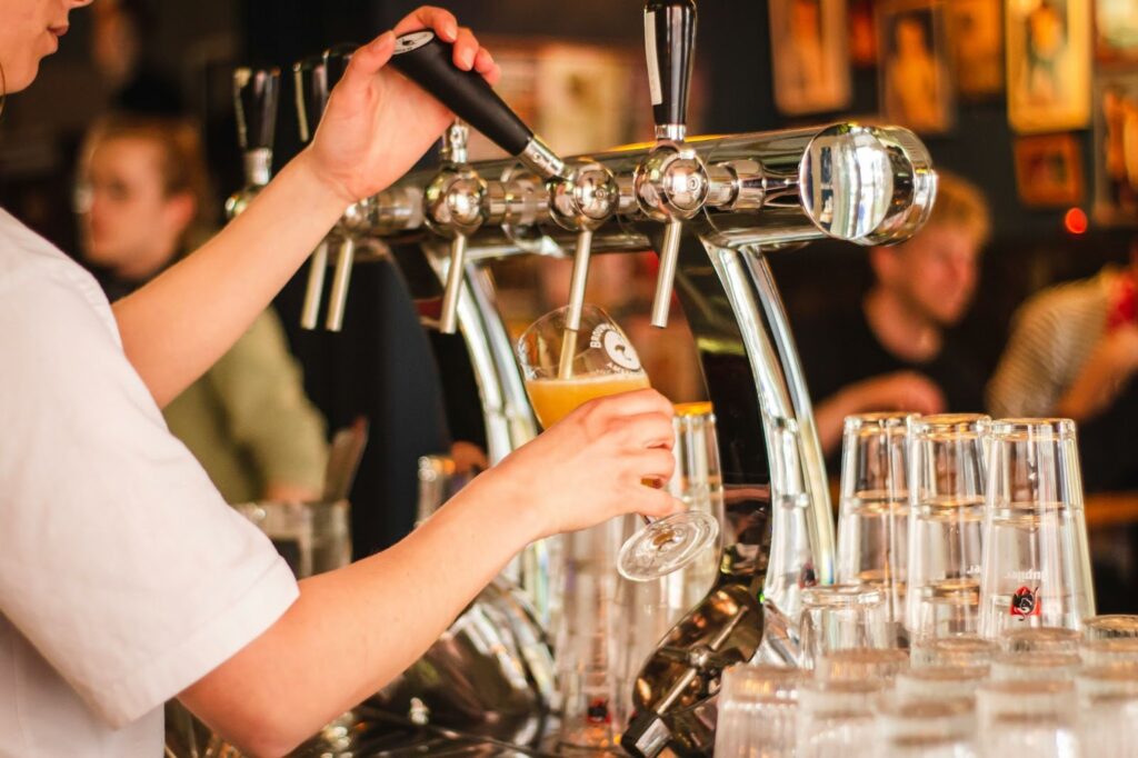 A person pours a beer from a tap in a brewery.