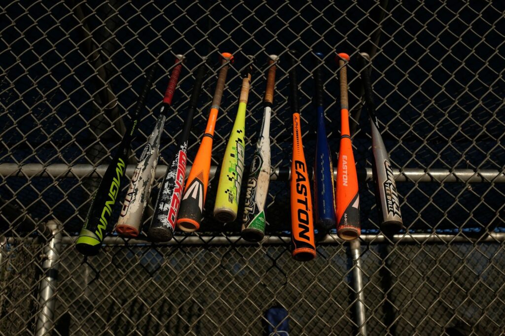 Aluminum baseball bats placed on a chain-link fence.
